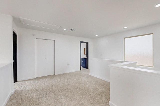 carpeted spare room featuring recessed lighting, visible vents, and attic access