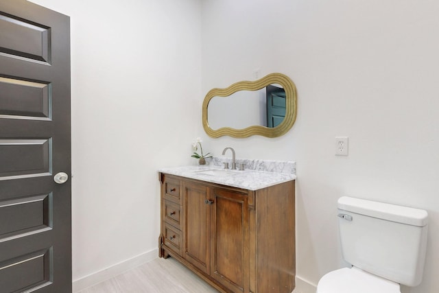 bathroom with vanity, baseboards, and toilet