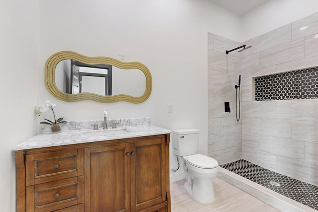 full bath featuring toilet, tiled shower, and vanity