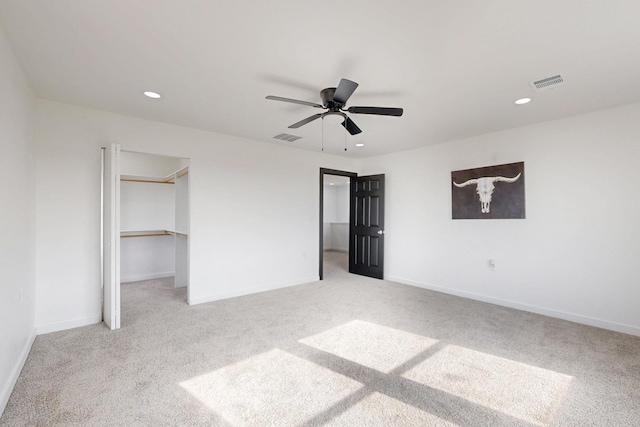 unfurnished bedroom with visible vents, a spacious closet, and light colored carpet