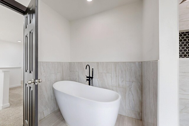 full bath featuring a freestanding tub, tile walls, wainscoting, and recessed lighting