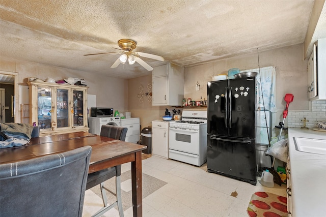 kitchen featuring white gas range, independent washer and dryer, white cabinetry, and black fridge