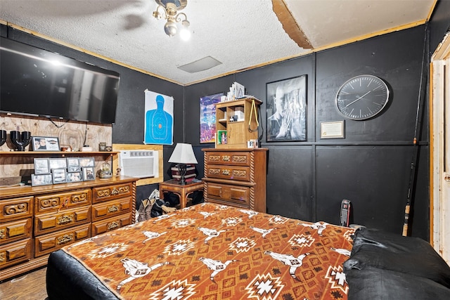 bedroom with an AC wall unit, wood-type flooring, and a textured ceiling