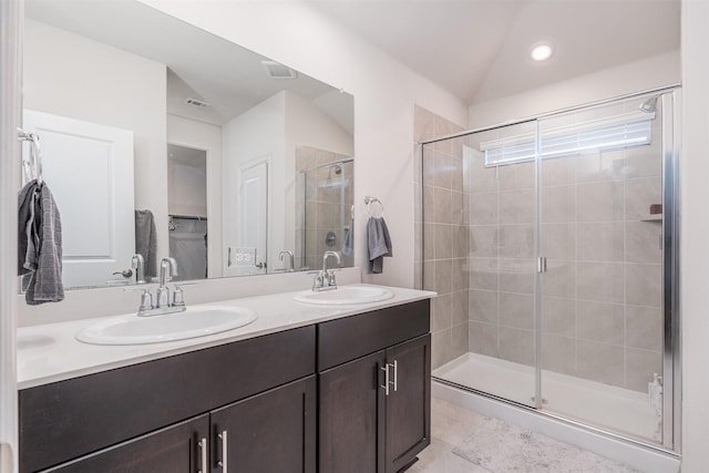 full bathroom with double vanity, a stall shower, visible vents, and a sink