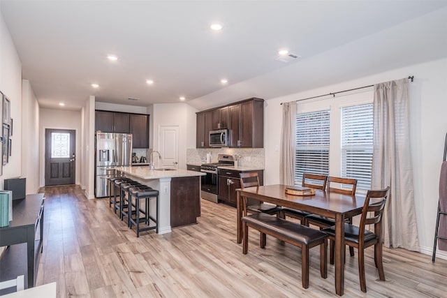 kitchen with a breakfast bar area, visible vents, appliances with stainless steel finishes, a sink, and an island with sink