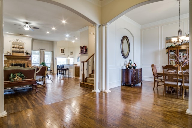 entryway with ceiling fan, dark wood-type flooring, decorative columns, and ornamental molding