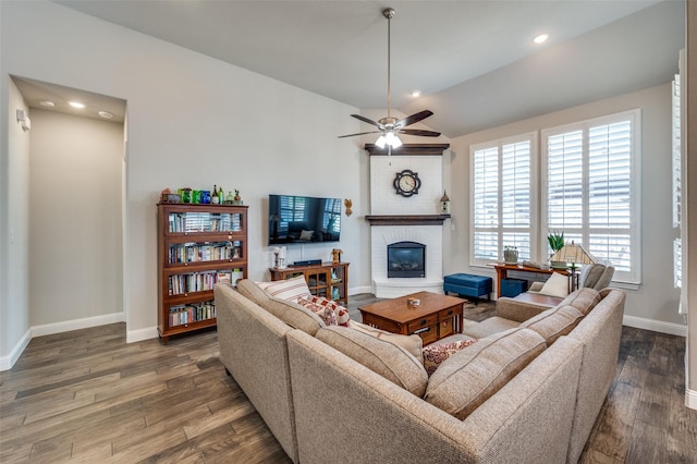 living room with ceiling fan, vaulted ceiling, a brick fireplace, and dark hardwood / wood-style flooring