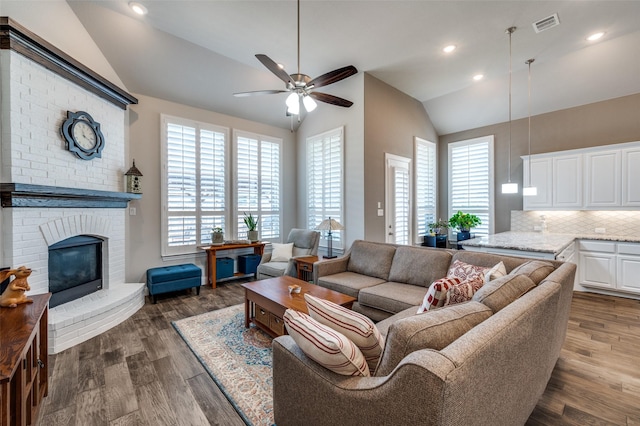 living room featuring ceiling fan, lofted ceiling, dark wood-type flooring, and a fireplace