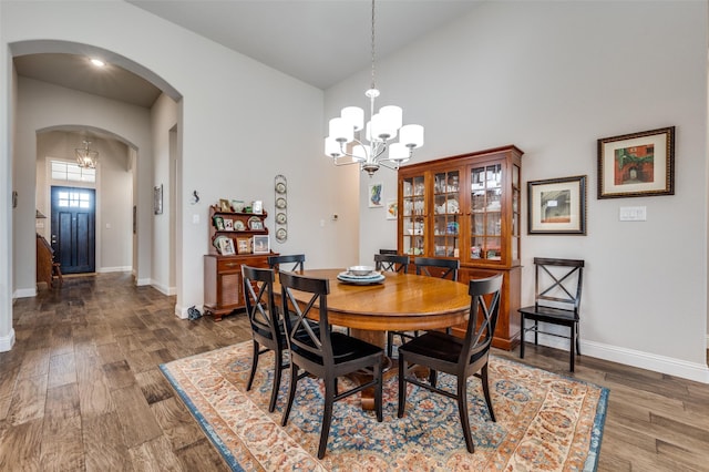 dining area with dark wood-type flooring, lofted ceiling, and a notable chandelier