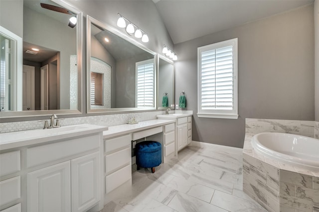 bathroom featuring a healthy amount of sunlight, lofted ceiling, vanity, and tiled tub