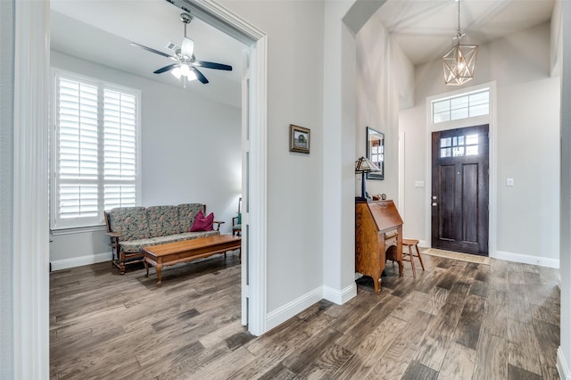 foyer entrance featuring ceiling fan with notable chandelier, dark hardwood / wood-style floors, and a healthy amount of sunlight