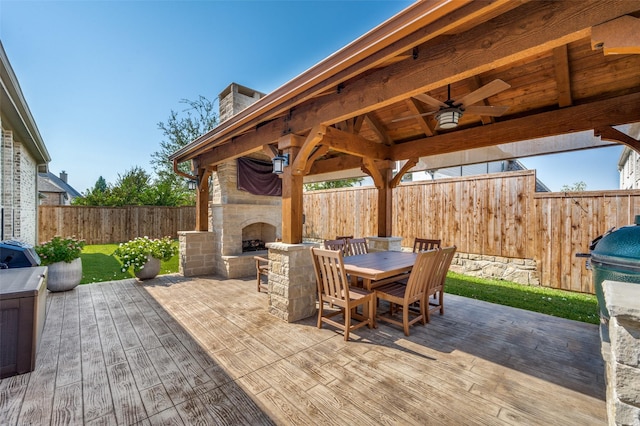 view of patio with an outdoor stone fireplace, a wooden deck, a gazebo, and ceiling fan