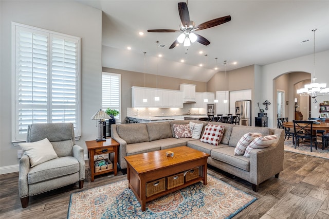 living room with ceiling fan with notable chandelier, vaulted ceiling, and hardwood / wood-style floors