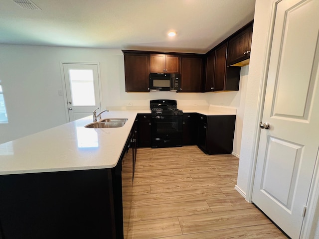 kitchen with kitchen peninsula, light hardwood / wood-style flooring, black appliances, sink, and dark brown cabinets