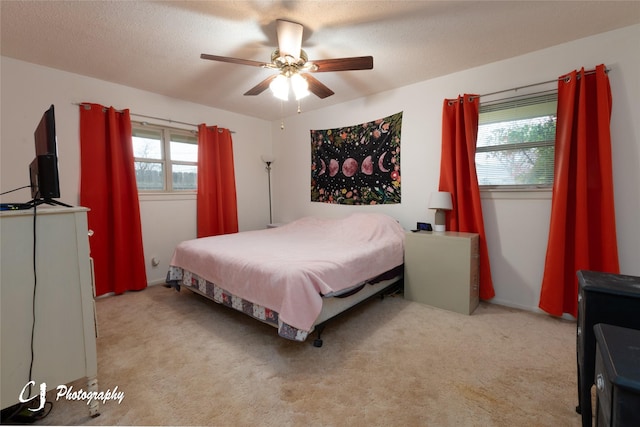 carpeted bedroom featuring ceiling fan and a textured ceiling