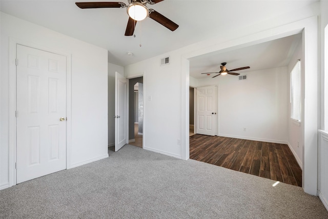 unfurnished bedroom with ceiling fan and dark colored carpet