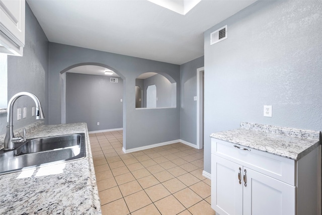 kitchen featuring light tile patterned floors, sink, white cabinetry, and light stone countertops