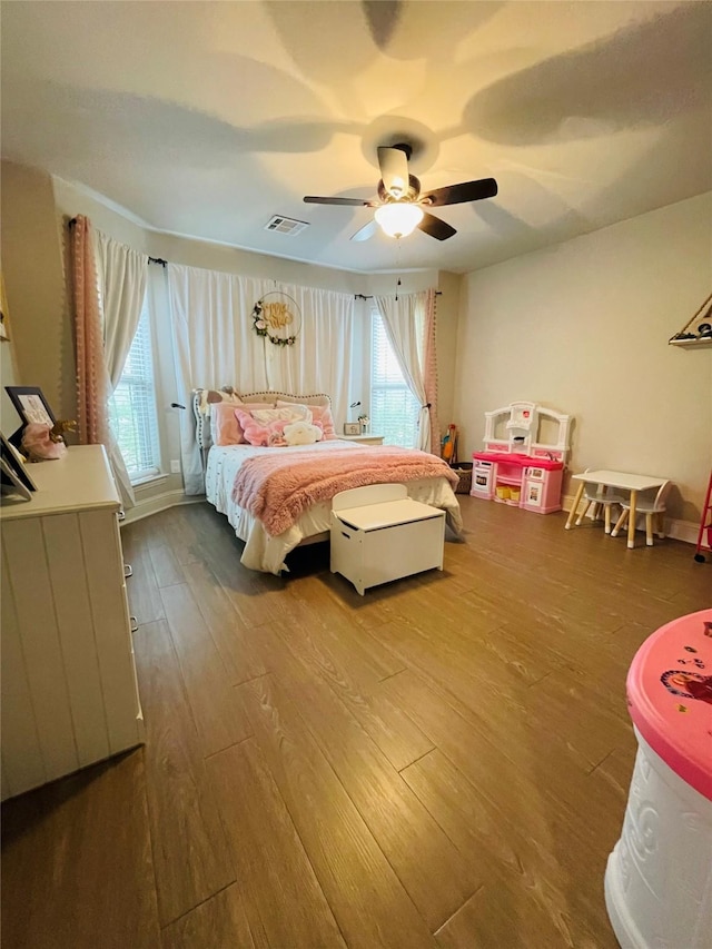 bedroom with multiple windows, wood-type flooring, and ceiling fan