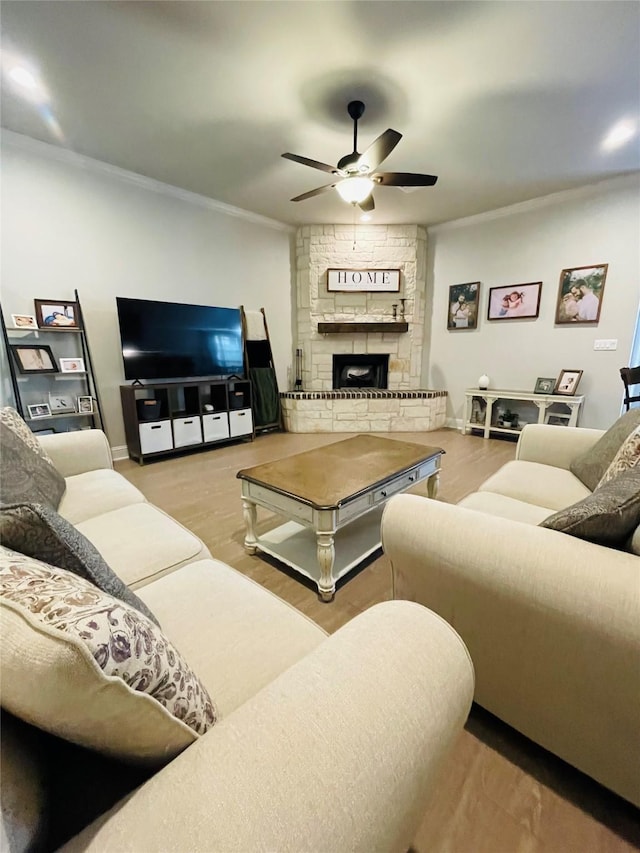 living room featuring a fireplace, ornamental molding, light wood-type flooring, and ceiling fan