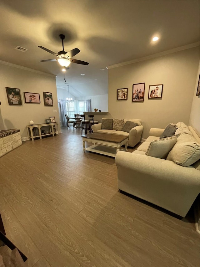 living room featuring hardwood / wood-style floors, crown molding, and ceiling fan with notable chandelier