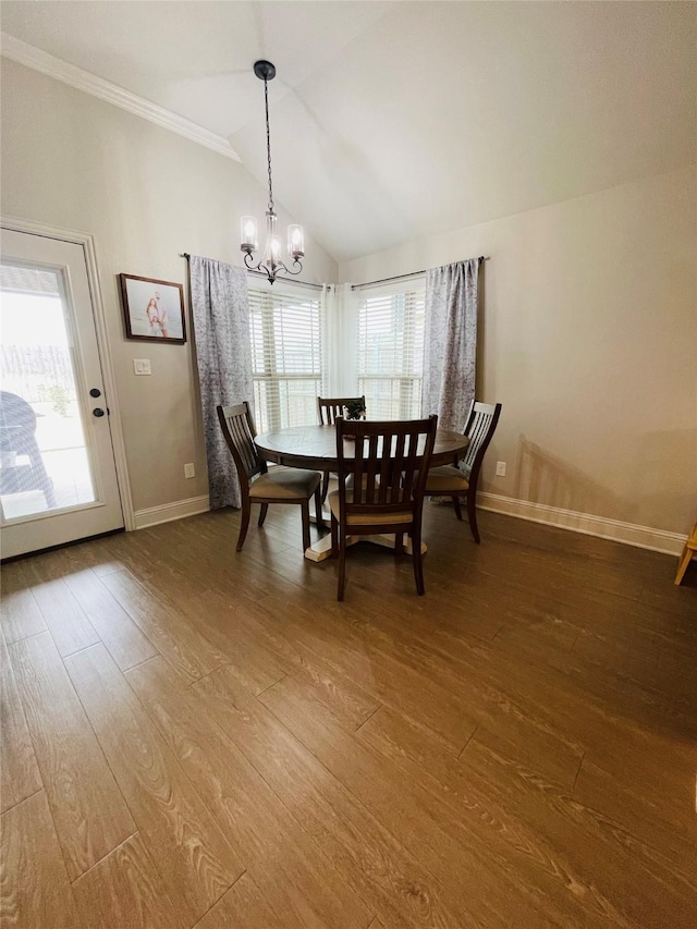 dining space featuring hardwood / wood-style floors, vaulted ceiling, an inviting chandelier, and ornamental molding