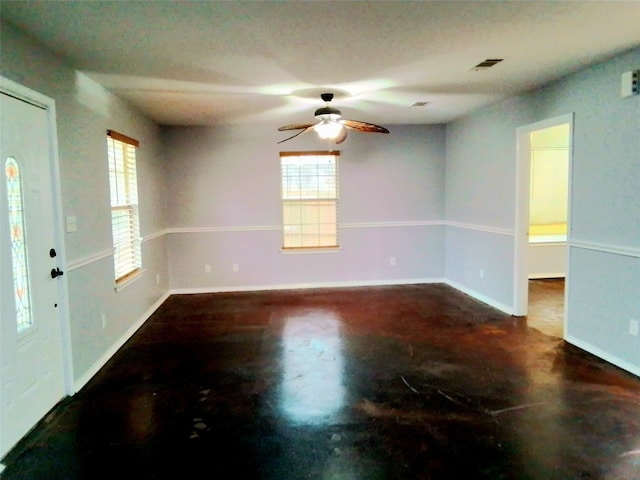 empty room featuring visible vents, ceiling fan, finished concrete flooring, and baseboards