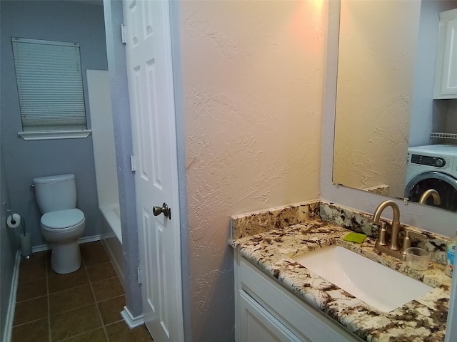 bathroom featuring washer / dryer, a textured wall, toilet, tile patterned floors, and vanity