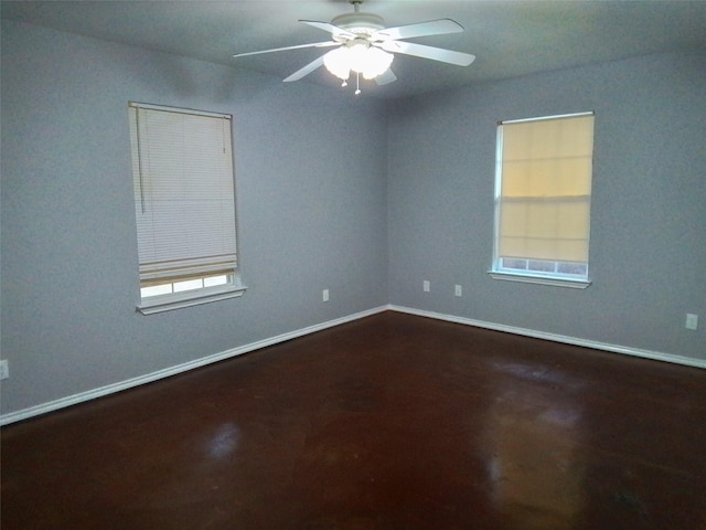 empty room featuring a ceiling fan, a wealth of natural light, and baseboards