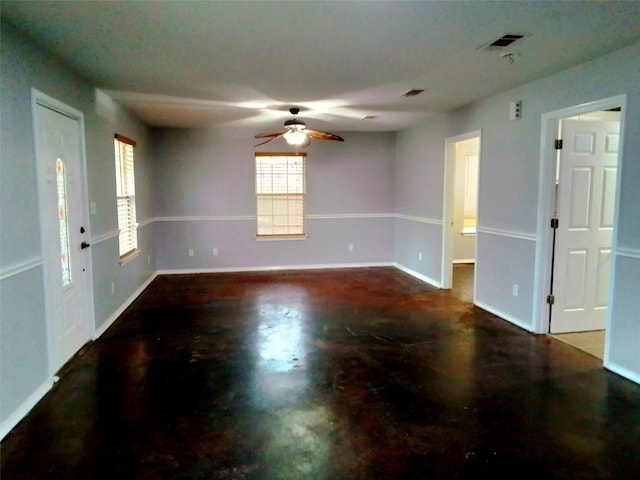 spare room with ceiling fan, concrete floors, baseboards, and visible vents