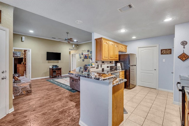 kitchen featuring kitchen peninsula, black appliances, ornamental molding, ceiling fan, and dark stone countertops