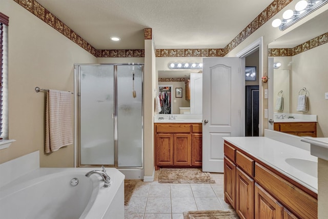 bathroom with a textured ceiling, independent shower and bath, tile patterned flooring, and vanity