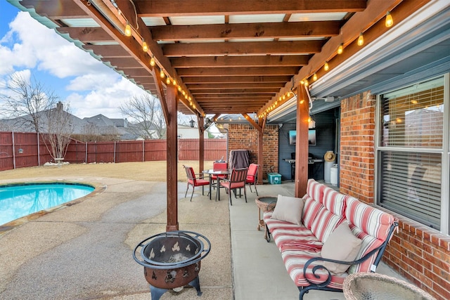 view of patio / terrace with a fire pit, a fenced in pool, and grilling area