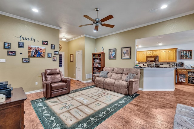 living room with ceiling fan, ornamental molding, and light wood-type flooring