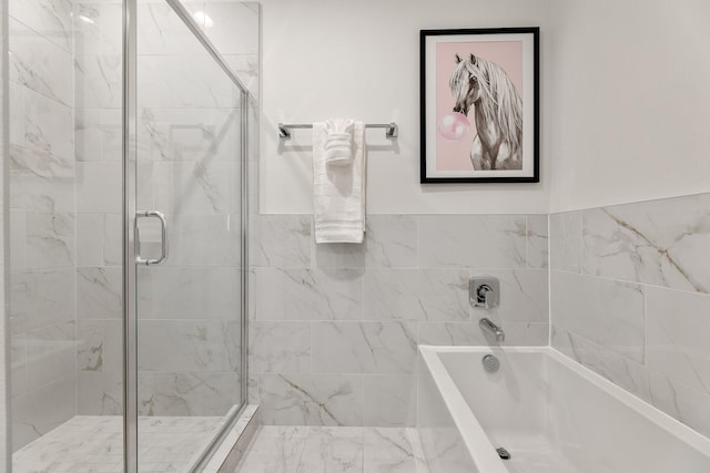 bathroom featuring shower with separate bathtub and tile walls