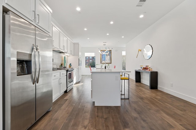 kitchen with an island with sink, white cabinetry, stainless steel appliances, and a breakfast bar