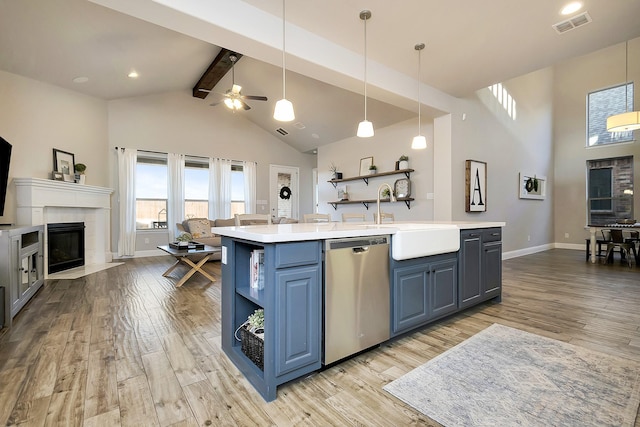 kitchen with an island with sink, light wood-type flooring, hanging light fixtures, sink, and dishwasher