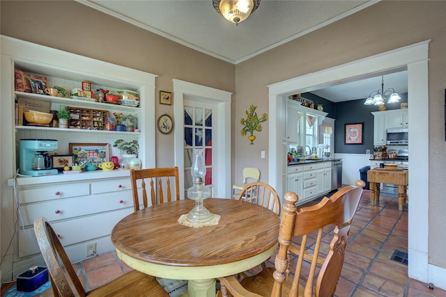 dining room featuring sink, ornamental molding, a notable chandelier, and tile patterned floors