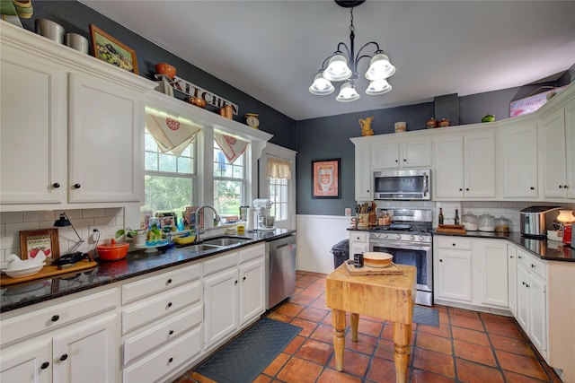 kitchen featuring sink, backsplash, decorative light fixtures, stainless steel appliances, and white cabinets