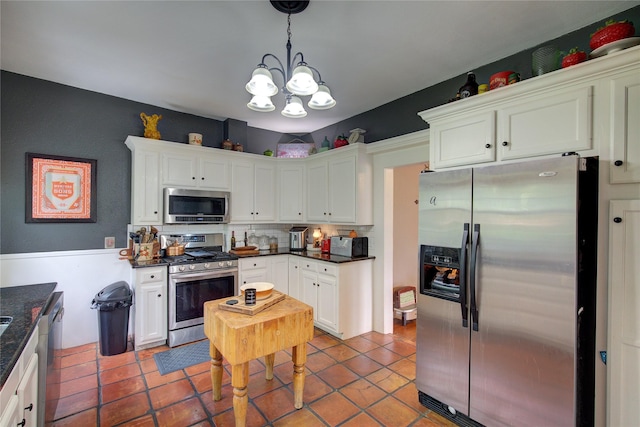 kitchen featuring hanging light fixtures, stainless steel appliances, white cabinets, and a notable chandelier