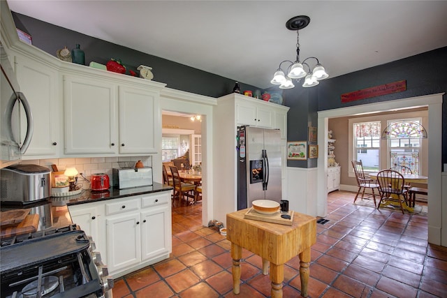 kitchen featuring white cabinets, plenty of natural light, pendant lighting, and stainless steel fridge with ice dispenser