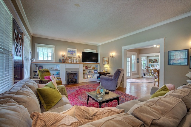 living room featuring a healthy amount of sunlight, light wood-type flooring, and ornamental molding