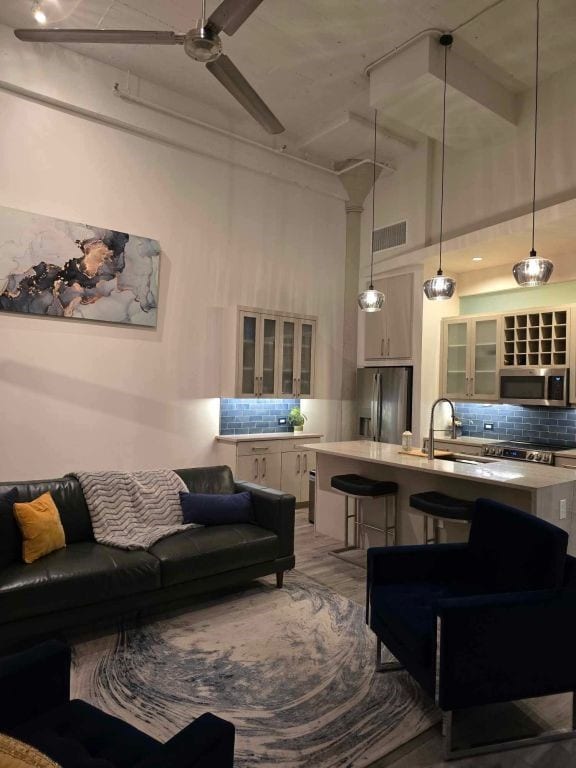 living room with ceiling fan, sink, a high ceiling, and light wood-type flooring