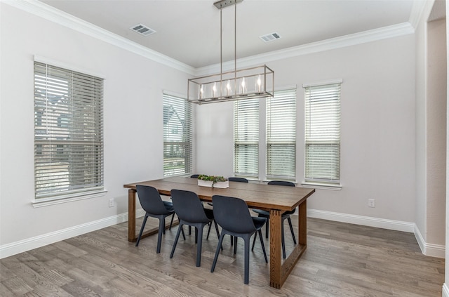 dining room with a notable chandelier, ornamental molding, and wood-type flooring