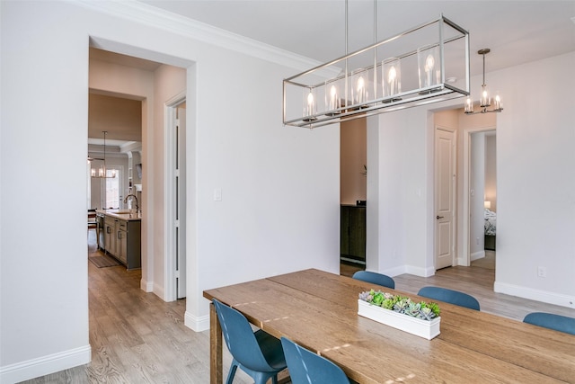 dining room featuring light hardwood / wood-style floors, a chandelier, sink, and crown molding