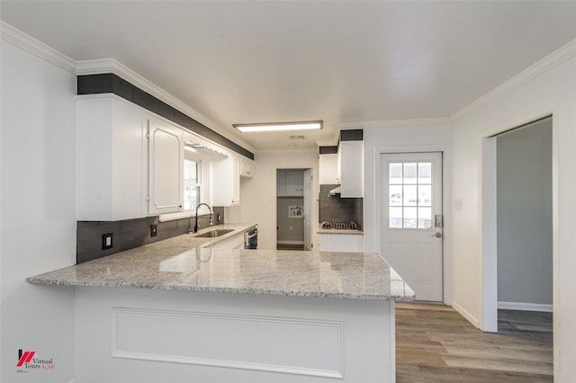 kitchen with kitchen peninsula, white cabinets, light stone counters, and light hardwood / wood-style flooring