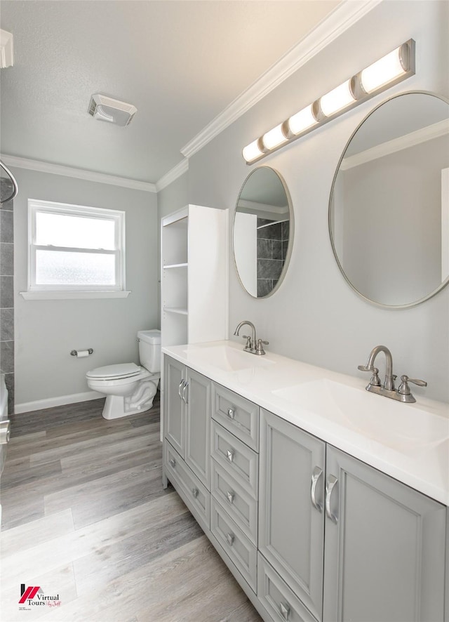 bathroom featuring wood-type flooring, vanity, crown molding, and toilet