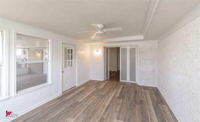 empty room with ceiling fan, dark hardwood / wood-style flooring, brick wall, and ornamental molding