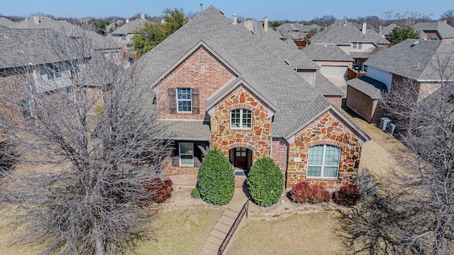 view of front of property with stone siding, brick siding, and roof with shingles