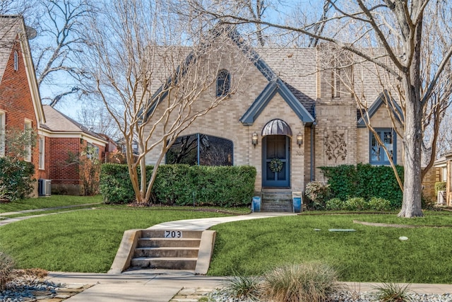 tudor-style house with brick siding and a front lawn