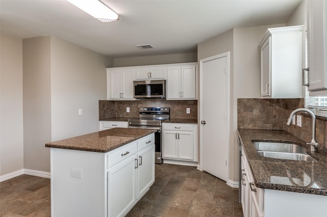 kitchen with sink, appliances with stainless steel finishes, a kitchen island, and white cabinetry